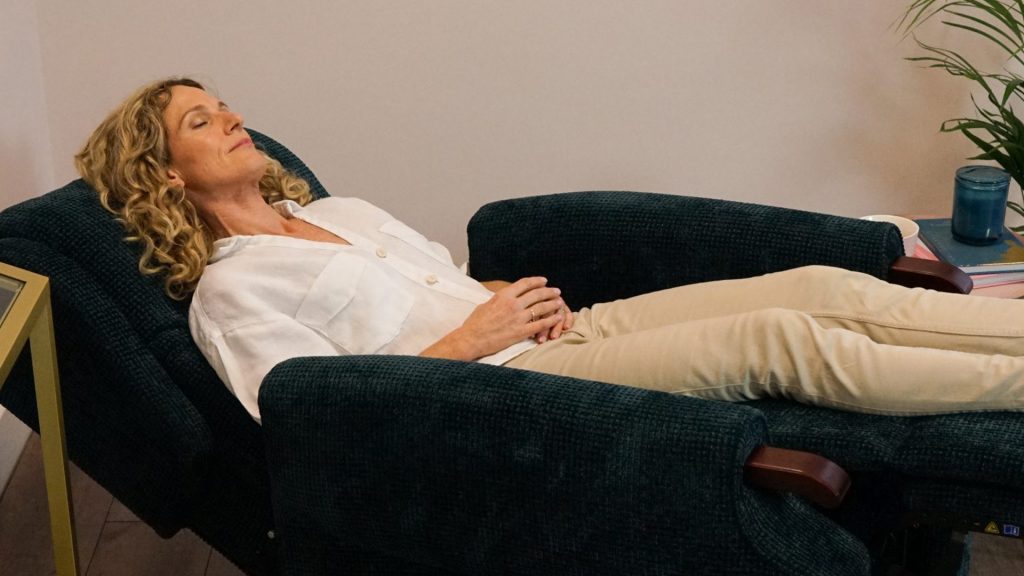 A person relaxingback into a riser recliner chair, “appearing” to be asleep or making themselves comfortable